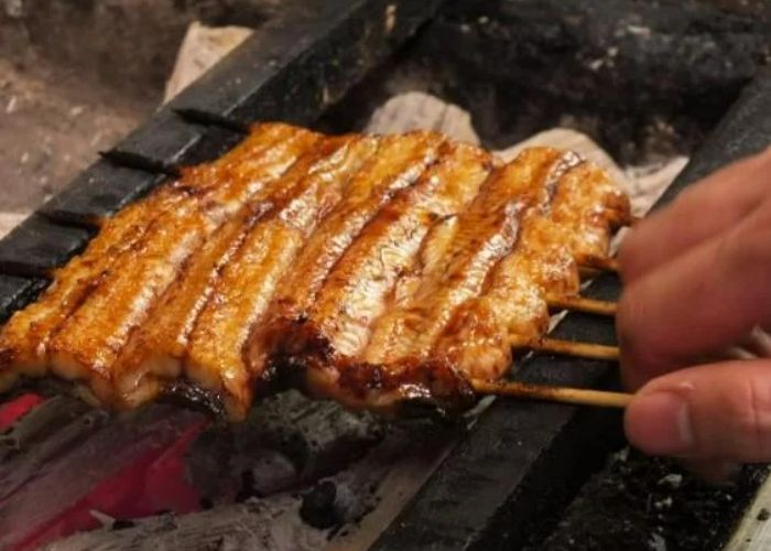 Skewered unagi eel at Unagi Uomasa, being cooked over charcoal.